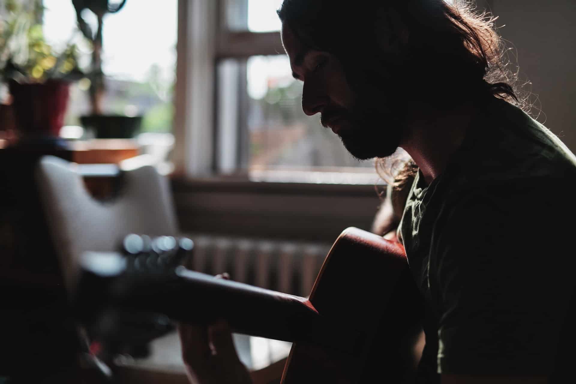 best way to learn acoustic guitar at home - man playing acoustic guitar at home