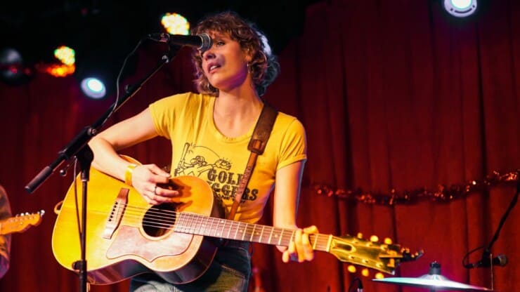 female guitarist wearing wrisband performing on stage