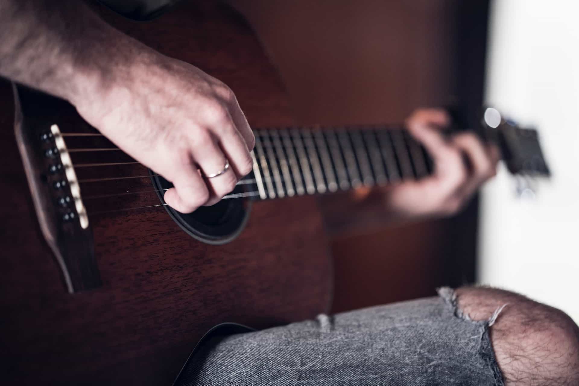 how long does it take to learn acoustic guitar - man playing acoustic guitar