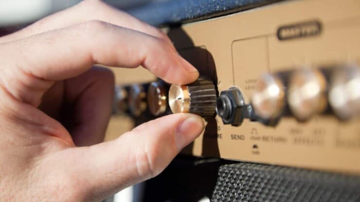 A focus of a person's hand adjusting amp controls