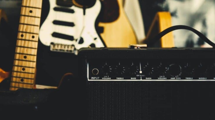 how to make a guitar amp sound better - focus photo of guitar amp with electric guitar in the behind
