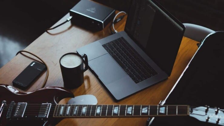 electric guitar, laptop, amp and cup of milk on office table