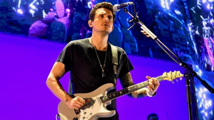 john mayer holding guitar performing on stage