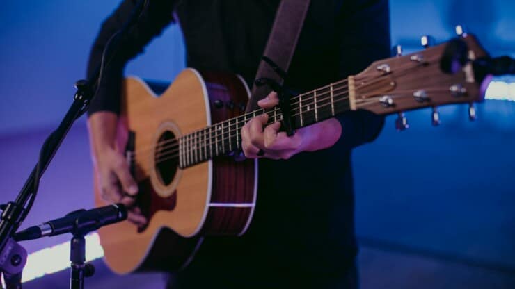 man playing guitar with capo