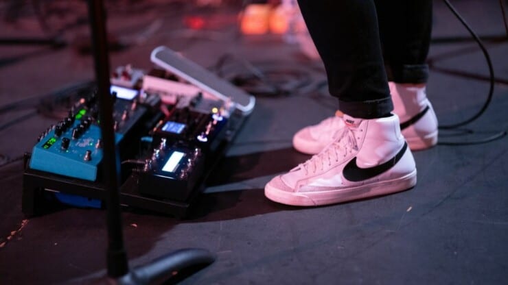 man playing guitar with distortion pedals and pedalboard in floor