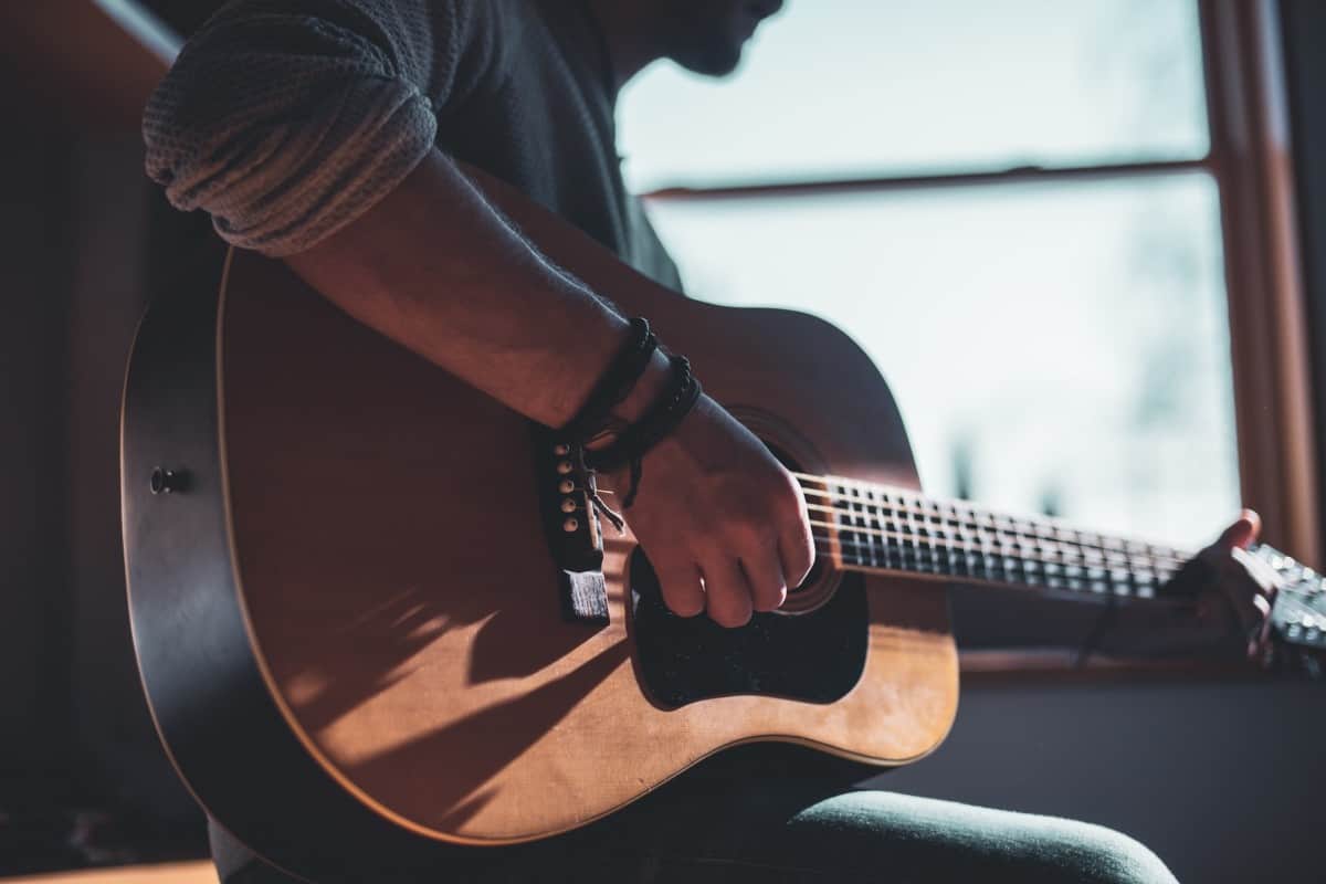 tips for learning guitar - man playing acoustic guitar