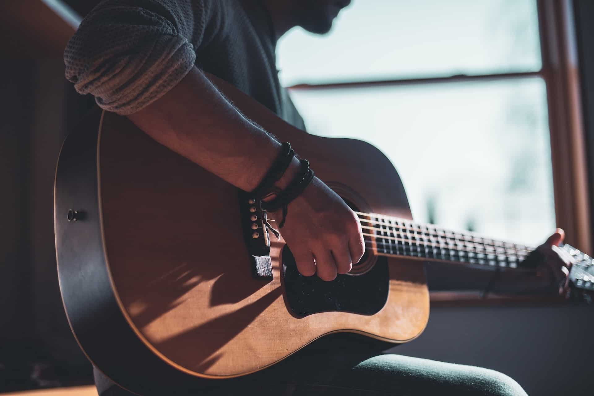 tips for learning guitar - man playing acoustic guitar