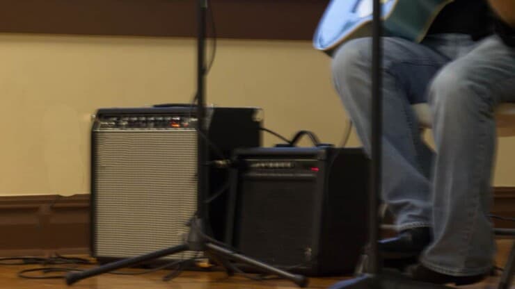 person playing guitar inside the room with amps