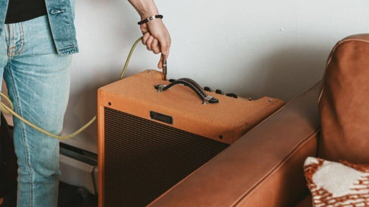 why is my guitar amp buzzing - man inserting cable on guitar amp